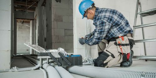 Electrician installs wiring in a commercial building under construction.